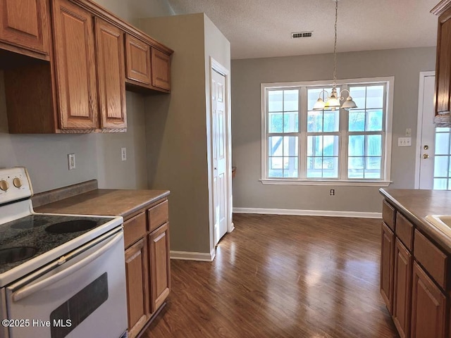 kitchen featuring dark wood-type flooring, an inviting chandelier, electric range, a textured ceiling, and decorative light fixtures