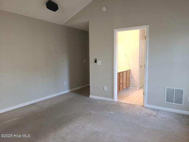 carpeted spare room with vaulted ceiling