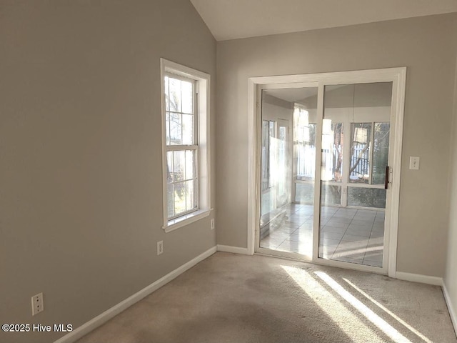 carpeted spare room featuring vaulted ceiling