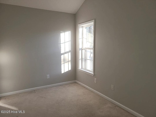 carpeted spare room with vaulted ceiling