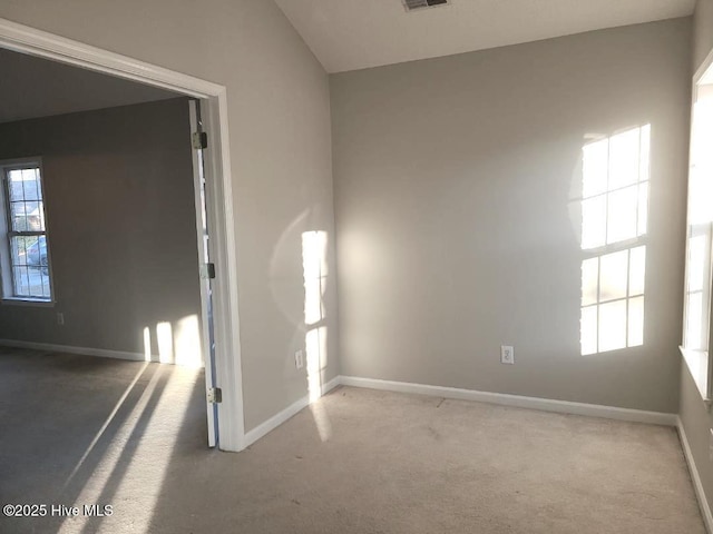 spare room with carpet flooring and vaulted ceiling