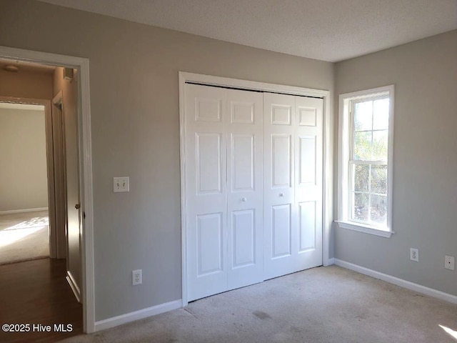 unfurnished bedroom featuring light carpet, a closet, and a textured ceiling