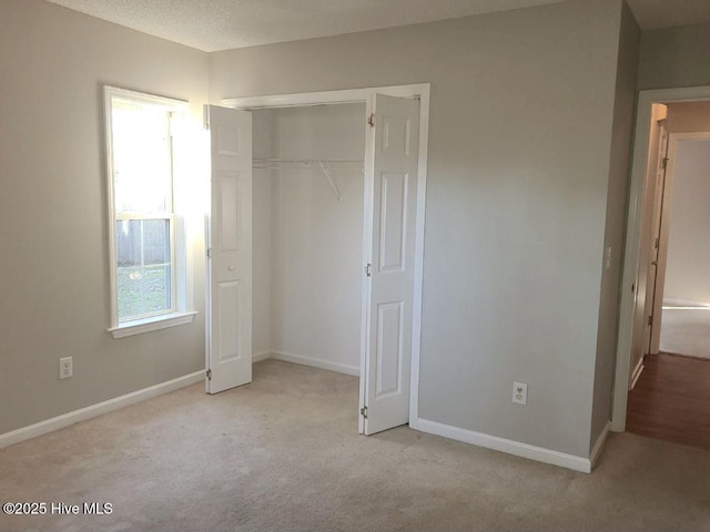 unfurnished bedroom with a textured ceiling, light carpet, and a closet