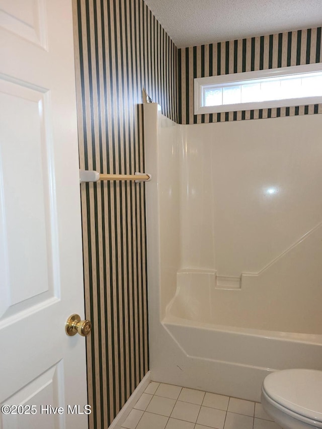 bathroom featuring tile patterned flooring, toilet, shower / bath combination, and a textured ceiling