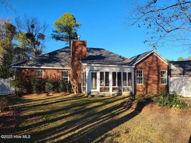 rear view of house with a yard and a sunroom