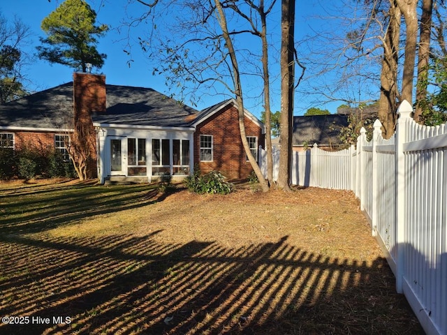 rear view of house featuring a lawn and a sunroom