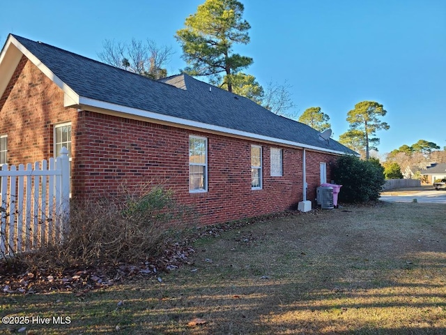 view of side of home with a yard and central AC unit