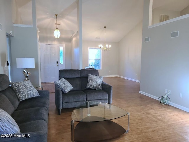 living room with wood-type flooring, high vaulted ceiling, and a chandelier