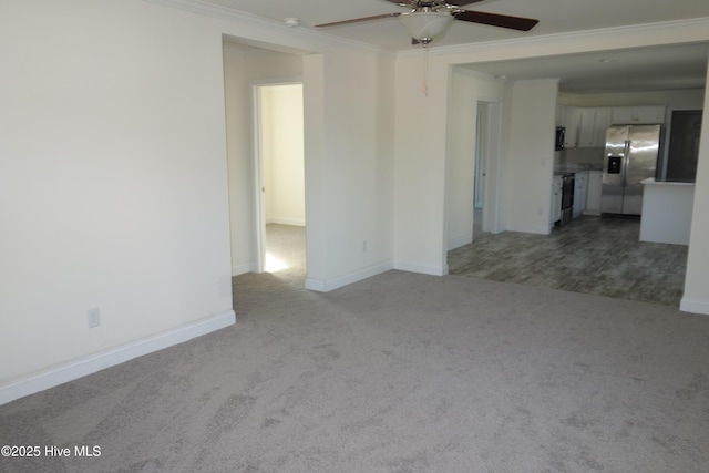 spare room with ceiling fan, ornamental molding, and light carpet