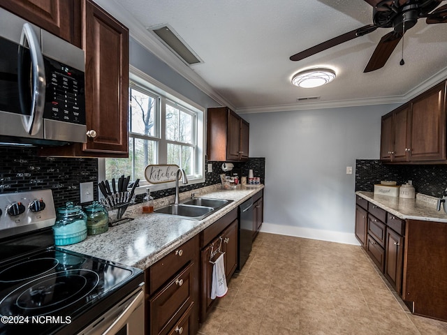 kitchen featuring light stone counters, ornamental molding, dark brown cabinetry, stainless steel appliances, and sink