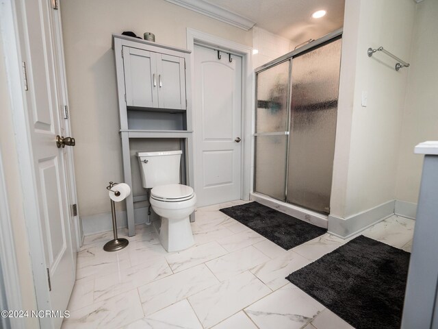 bathroom with crown molding, a shower with shower door, and toilet