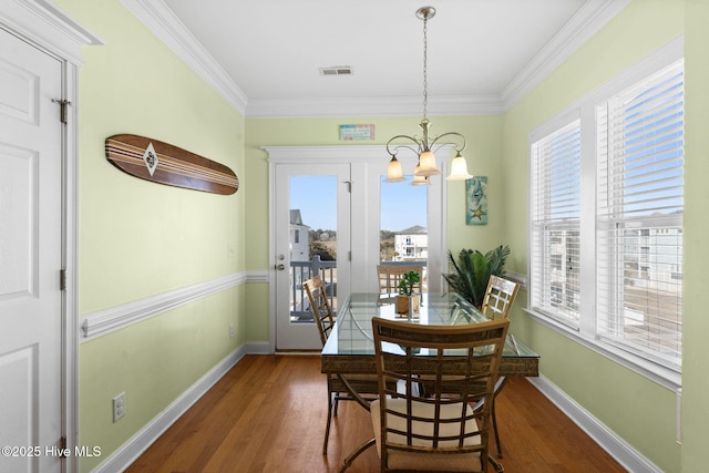 dining area featuring crown molding, baseboards, a notable chandelier, and wood finished floors