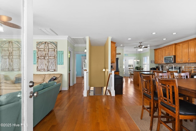 dining area featuring a ceiling fan, baseboards, recessed lighting, wood finished floors, and ornamental molding