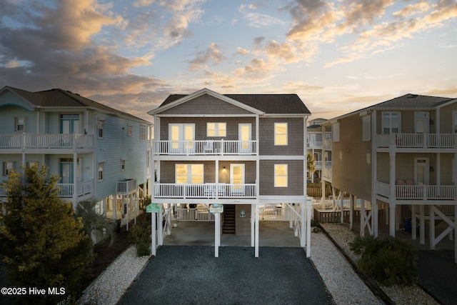 back house at dusk featuring a carport, a balcony, and cooling unit