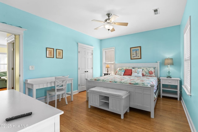 bedroom featuring light wood-style floors, baseboards, ceiling fan, and visible vents
