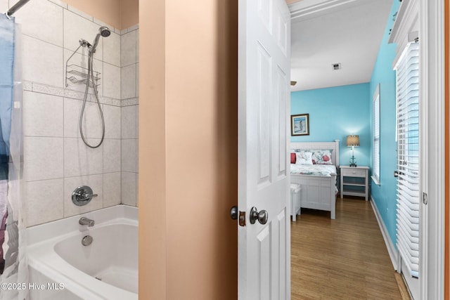 ensuite bathroom featuring visible vents, wood finished floors, bathing tub / shower combination, baseboards, and connected bathroom