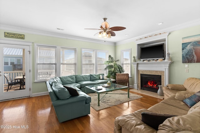 living room with wood-type flooring, ornamental molding, ceiling fan, and a high end fireplace