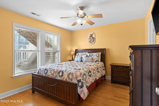 bedroom with light wood-style floors, baseboards, ceiling fan, and visible vents