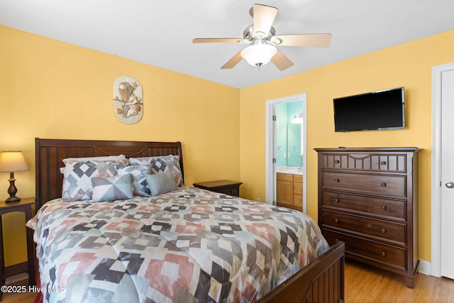 bedroom with a ceiling fan, ensuite bath, and light wood-type flooring