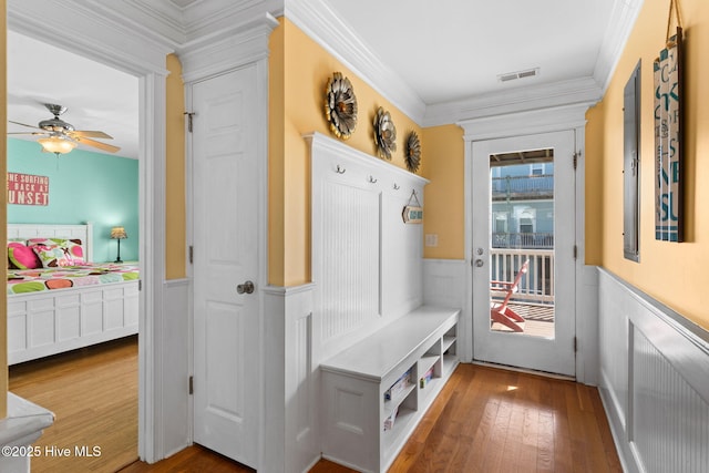 mudroom with crown molding, a decorative wall, and wainscoting