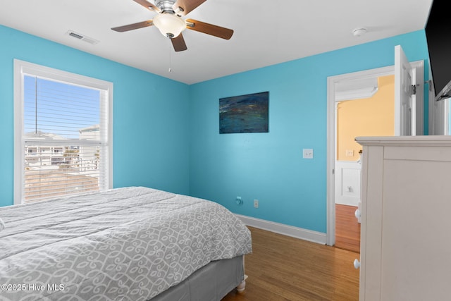 bedroom featuring ceiling fan, baseboards, visible vents, and wood finished floors