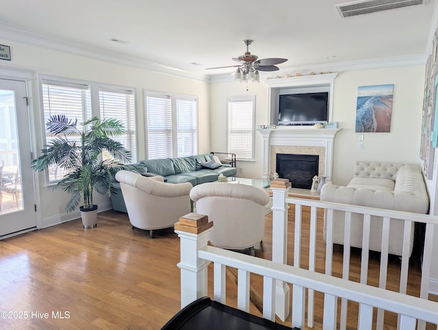 living area featuring visible vents, ornamental molding, light wood finished floors, and ceiling fan