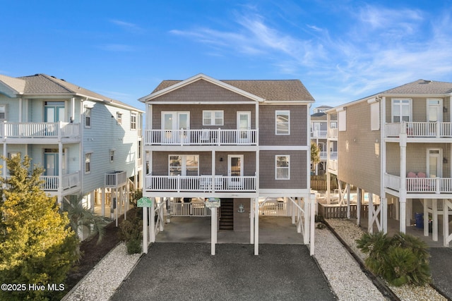 rear view of property with central air condition unit, driveway, a balcony, and a carport