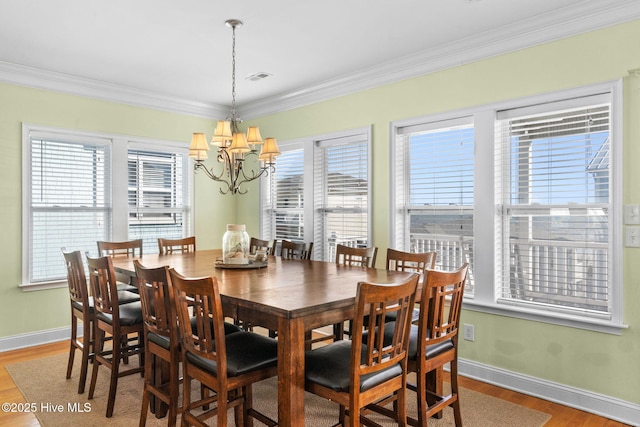 dining room featuring crown molding, an inviting chandelier, light wood-style floors, baseboards, and visible vents