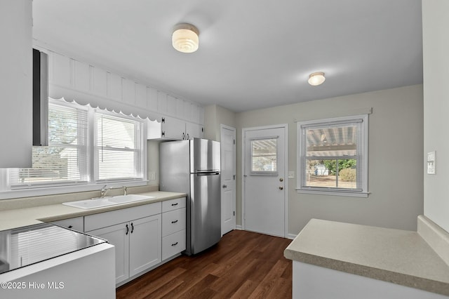 kitchen featuring sink, stainless steel fridge, white cabinets, and plenty of natural light