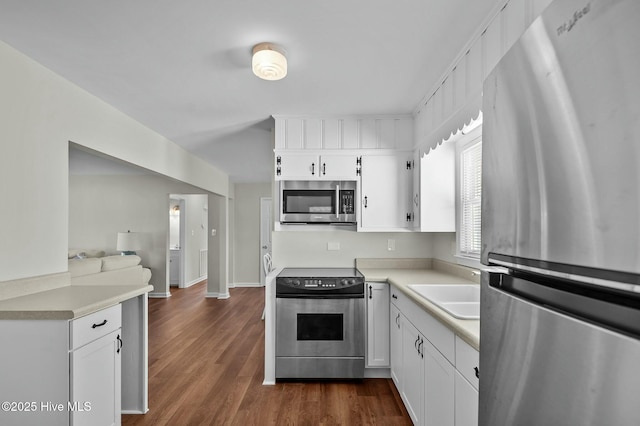 kitchen with appliances with stainless steel finishes, sink, dark wood-type flooring, and white cabinets