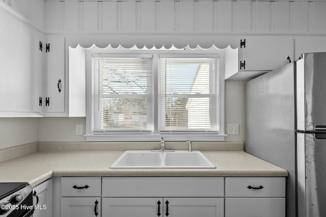 kitchen featuring white cabinetry, stainless steel fridge, and sink