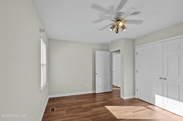 unfurnished bedroom with ceiling fan, dark hardwood / wood-style floors, and a closet