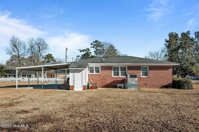 rear view of property with a carport and a yard