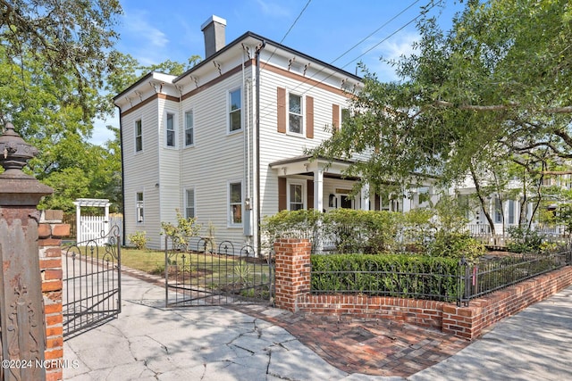 italianate home featuring a fenced front yard, a gate, and a chimney