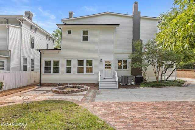 rear view of property with cooling unit, a chimney, and fence