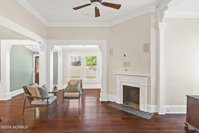 living area with ceiling fan, dark hardwood / wood-style flooring, crown molding, and ornate columns