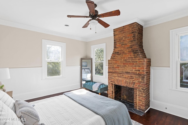 bedroom featuring a fireplace, dark hardwood / wood-style floors, ceiling fan, and crown molding