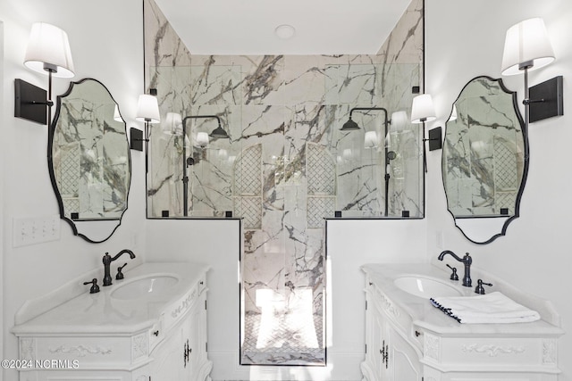 full bath with a sink, a marble finish shower, and two vanities