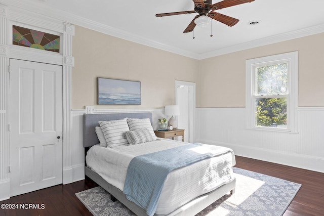 bedroom featuring visible vents, crown molding, ceiling fan, a wainscoted wall, and wood finished floors