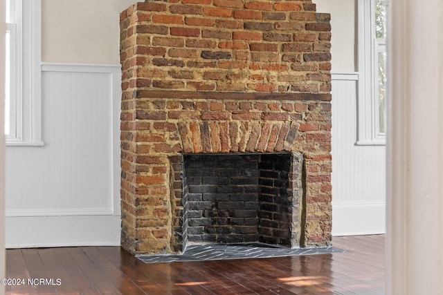 interior details featuring wainscoting, a brick fireplace, and wood finished floors