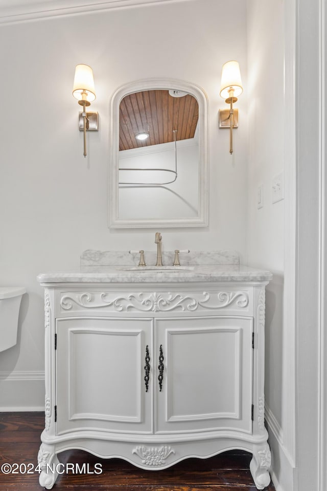 half bath featuring vanity, baseboards, and wood finished floors