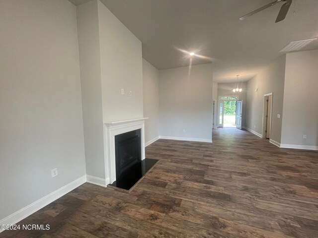 unfurnished living room featuring dark wood-type flooring and ceiling fan with notable chandelier