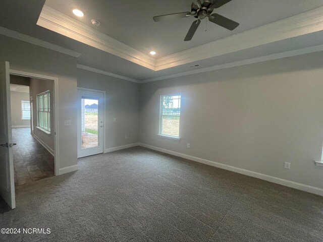 unfurnished room with dark colored carpet, plenty of natural light, and a raised ceiling