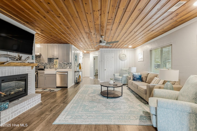 living room featuring wooden ceiling, ceiling fan, ornamental molding, a fireplace, and hardwood / wood-style flooring