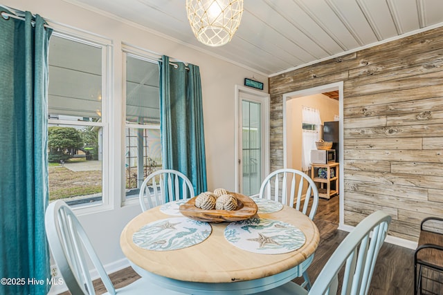 dining space with wood walls, a notable chandelier, hardwood / wood-style flooring, and crown molding