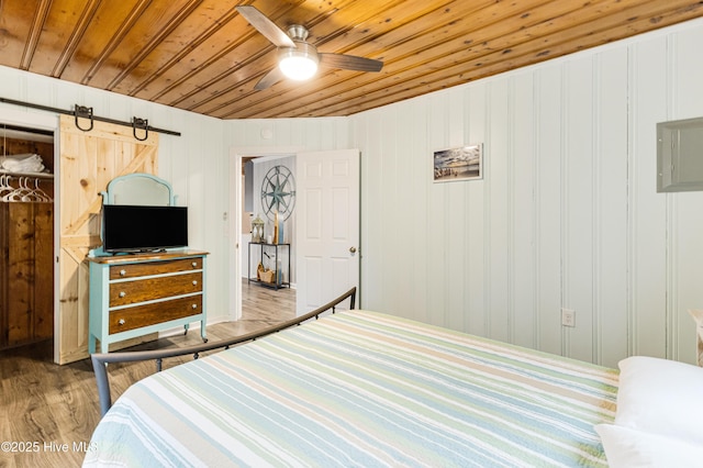 bedroom featuring a barn door, ceiling fan, light hardwood / wood-style floors, and wood ceiling