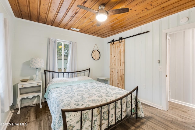 bedroom featuring wood ceiling, a barn door, ceiling fan, ornamental molding, and hardwood / wood-style flooring