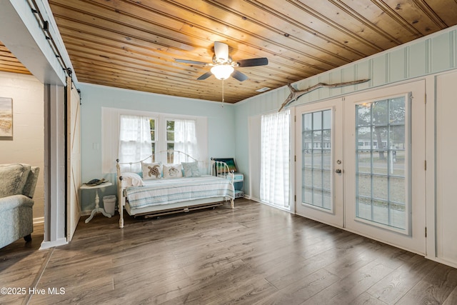 unfurnished bedroom with a barn door, wooden ceiling, ceiling fan, access to exterior, and wood-type flooring