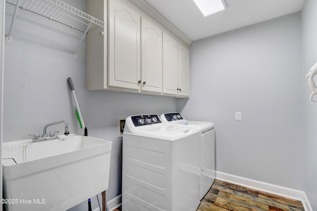 washroom featuring cabinets, dark hardwood / wood-style flooring, washing machine and clothes dryer, and sink