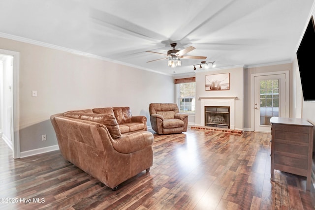 living room featuring ceiling fan, ornamental molding, dark wood-type flooring, and a brick fireplace